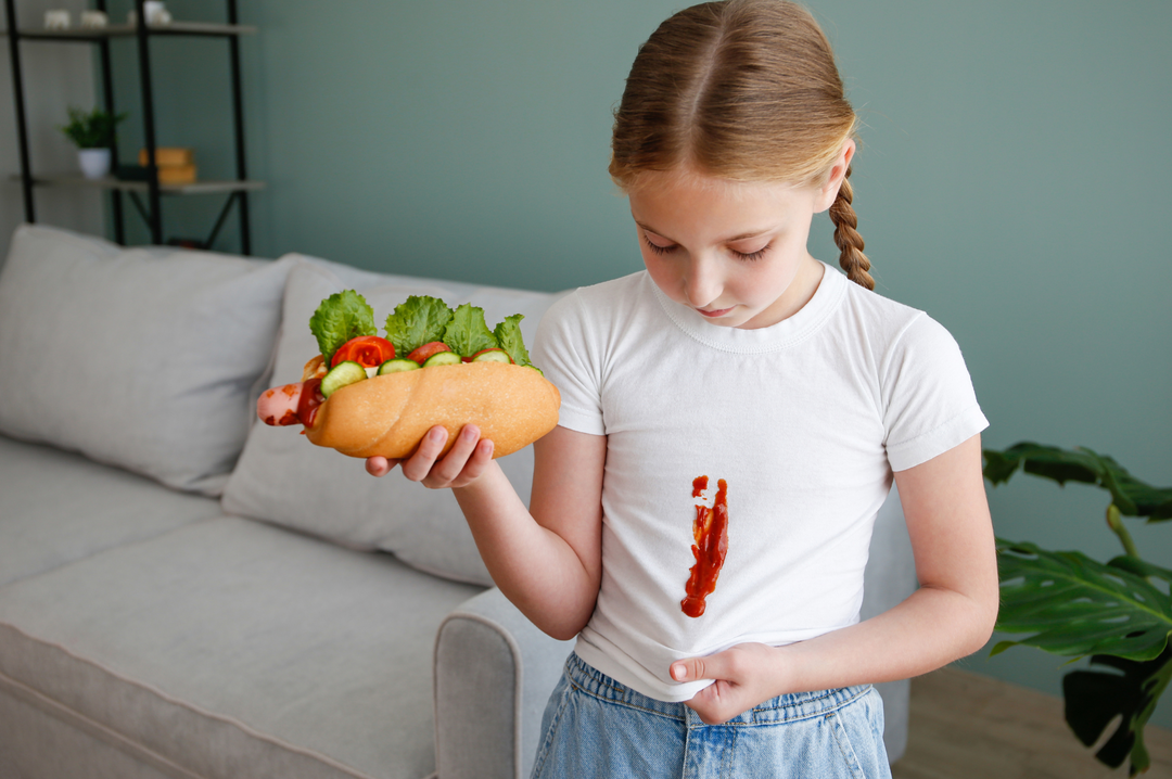 Girl Holding Sandwich with Ketchup on White Shirt