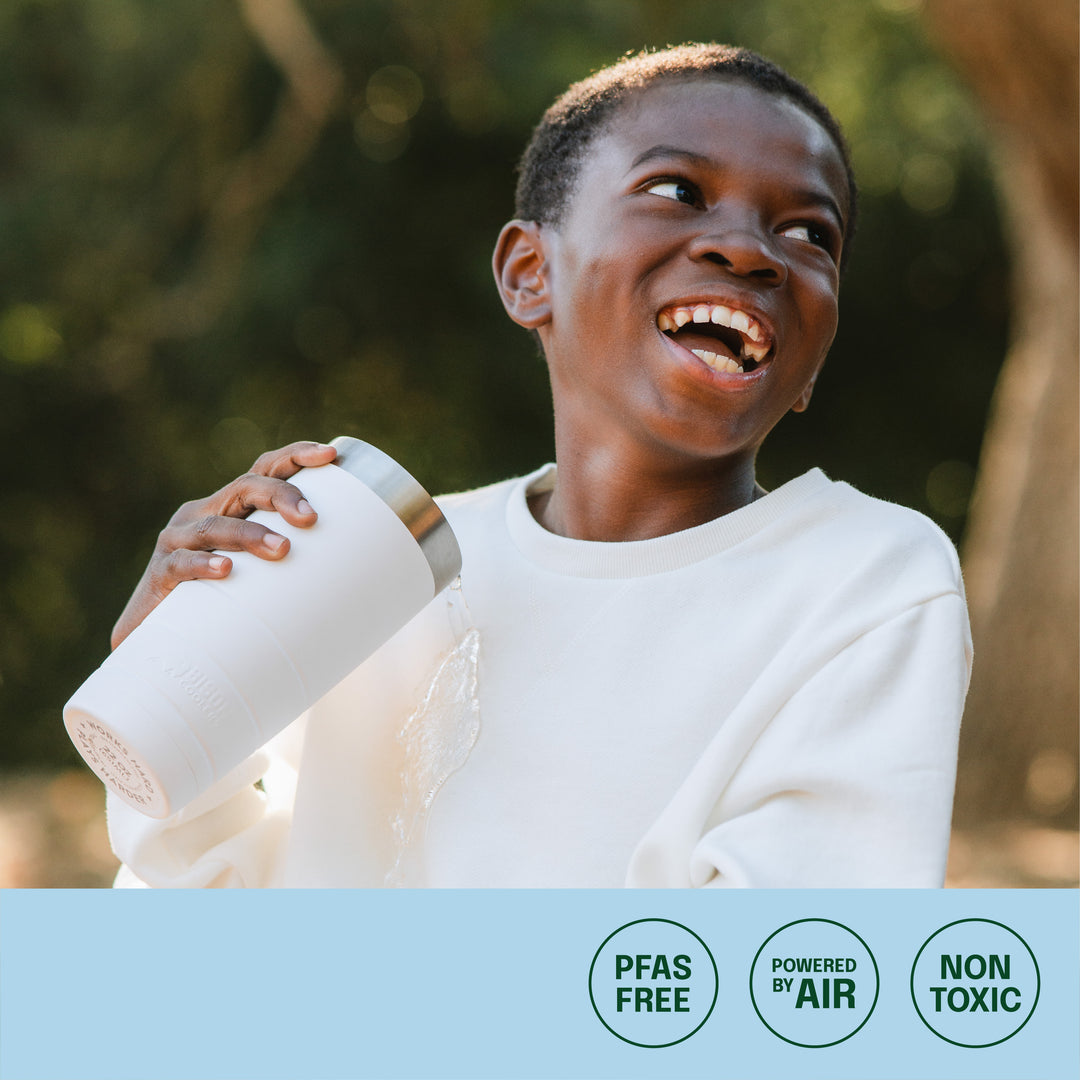 young boy spilling water on fabric protected sweatshirt, icons of PFAS-free, powered by air, non toxic