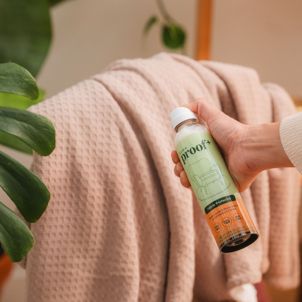 lady spraying Home Fabric Protector on a throw
