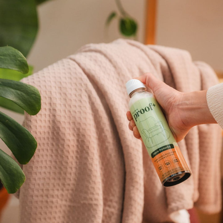 lady spraying Home Fabric Protector on a throw