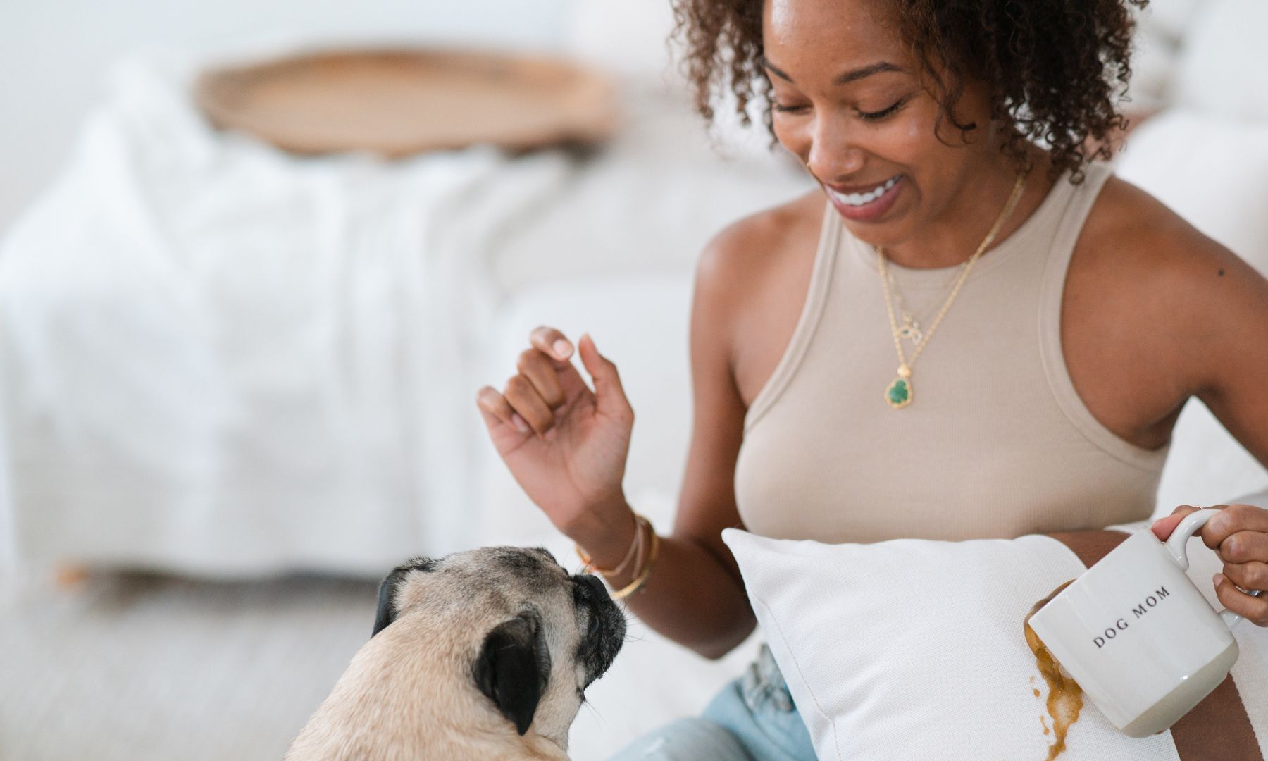 lady spilling coffee onto a waterproof couch pillow when she is playing with dog