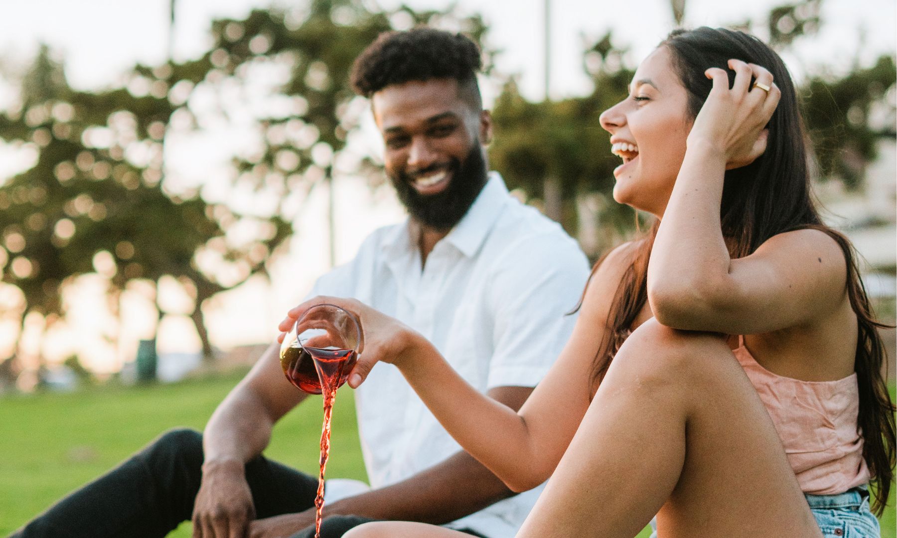 young adults sit together outside and pouring liquid on shoes that are stain free