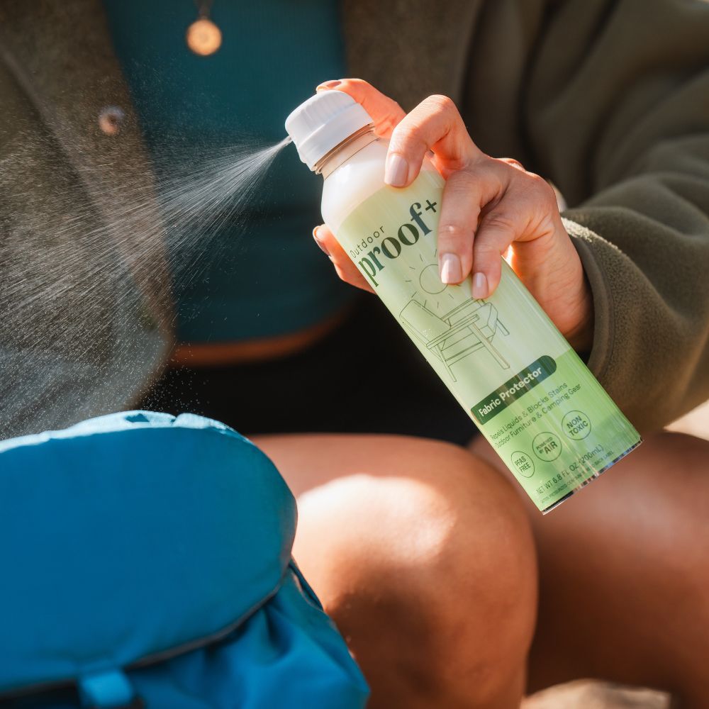 woman spraying outdoor backpack with ProofPlus Outdoor Fabric Protector