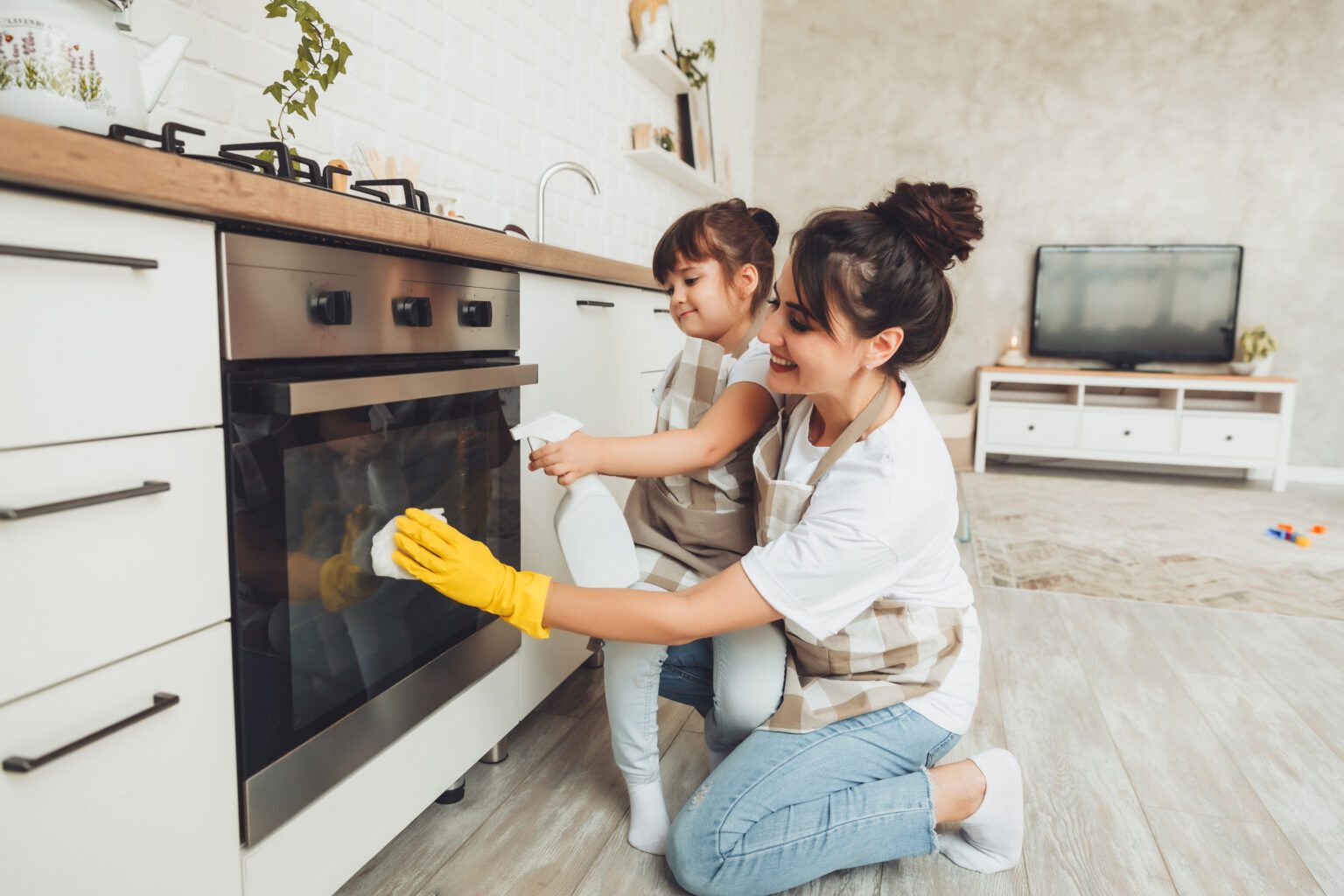 mom and daughter cleaning oven door