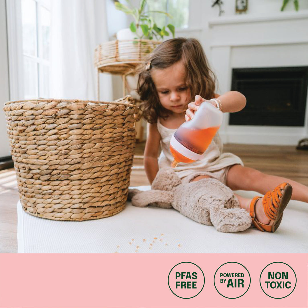 baby pouring juice on rug with sustainability messaging of PFAS free, Powered by air, Non-Toxic