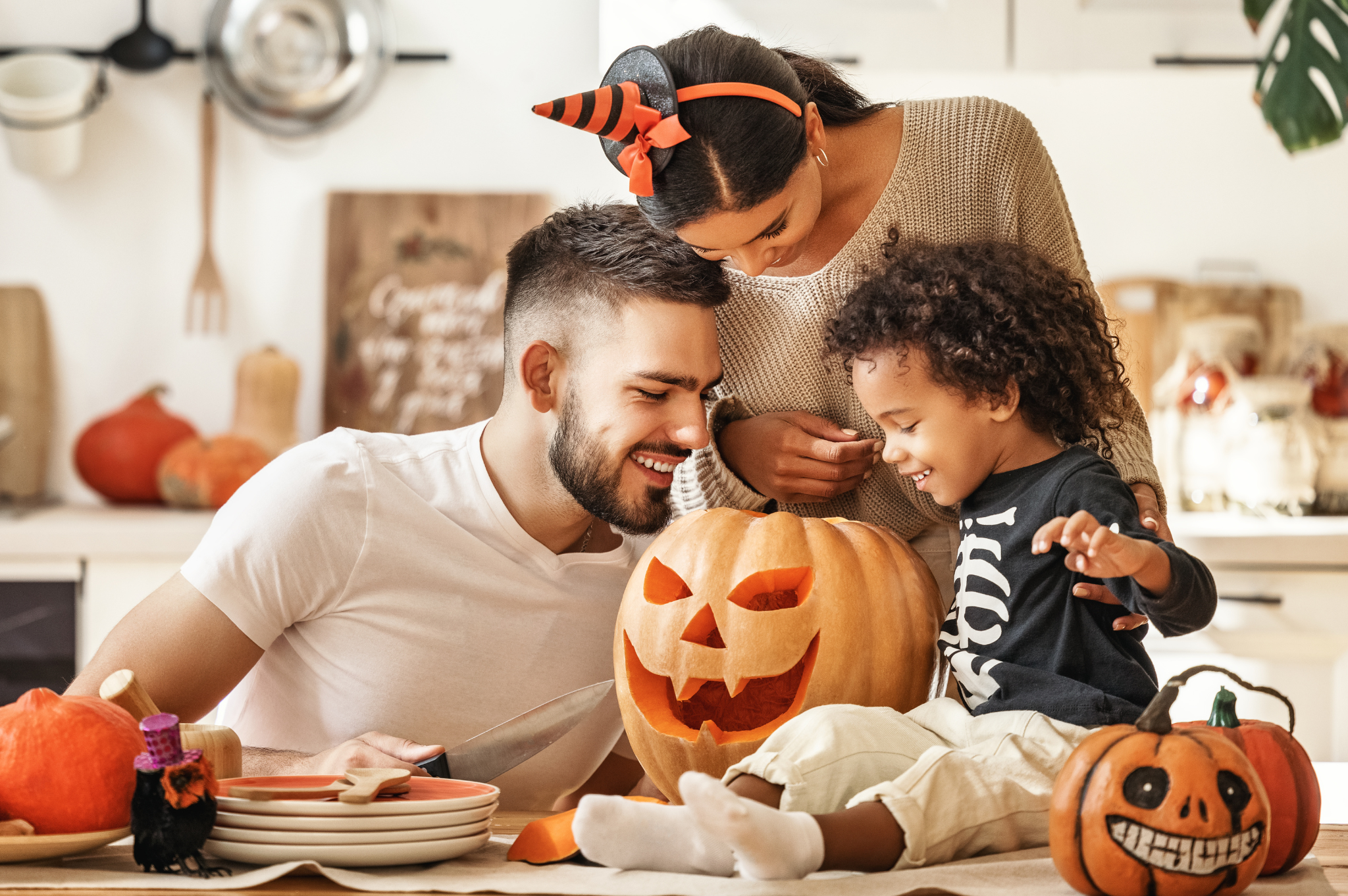 young family, dad mom and son looking inside a jack-o-lantern decorated for Halloween