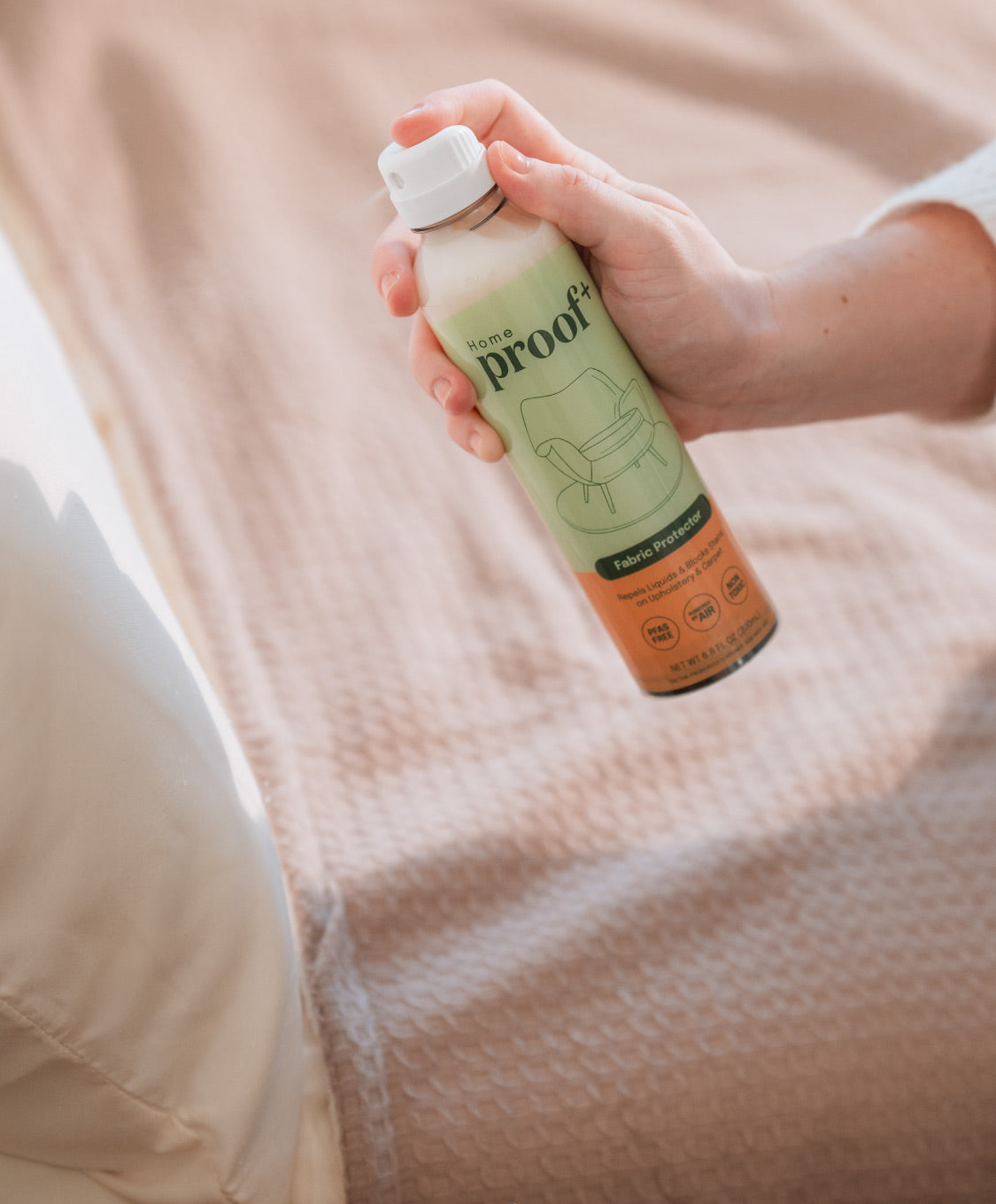 ProofPlus home bottle being sprayed onto bed upholstery