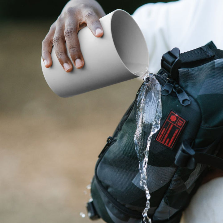 boy pouring water that rolls off a protected outdoor gear bag