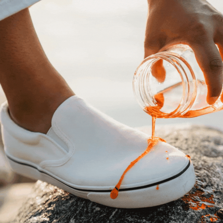 orange liquid rolling off white stain-free shoe that has been sprayed with shoe protector